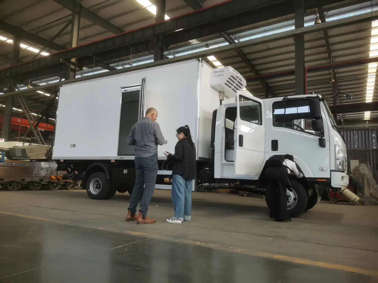 Overseas buyer reviewing a refrigerated vehicle during a factory visit