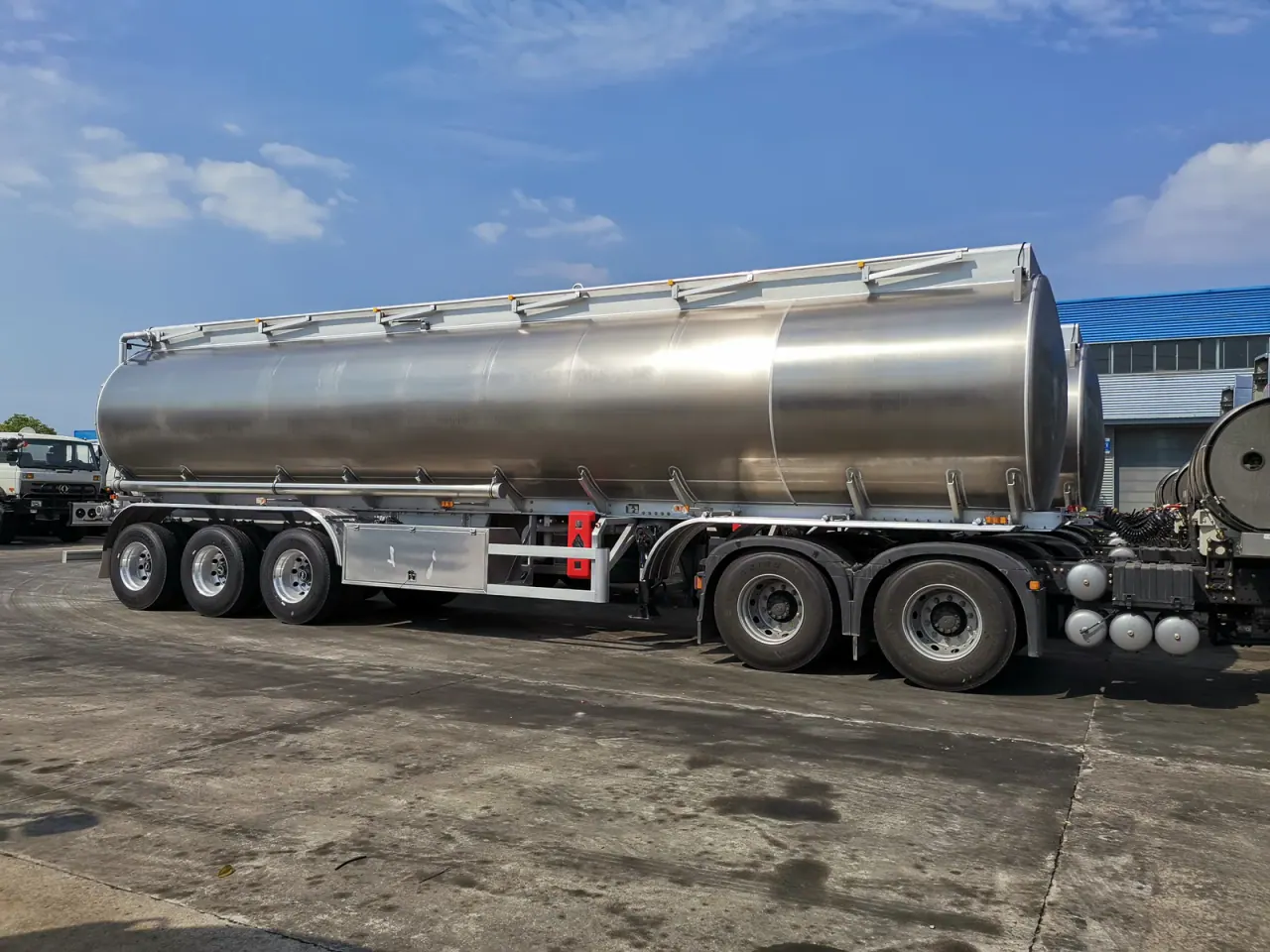 Three-axle metallic tanker semi-trailer viewed broadside in a factory yard