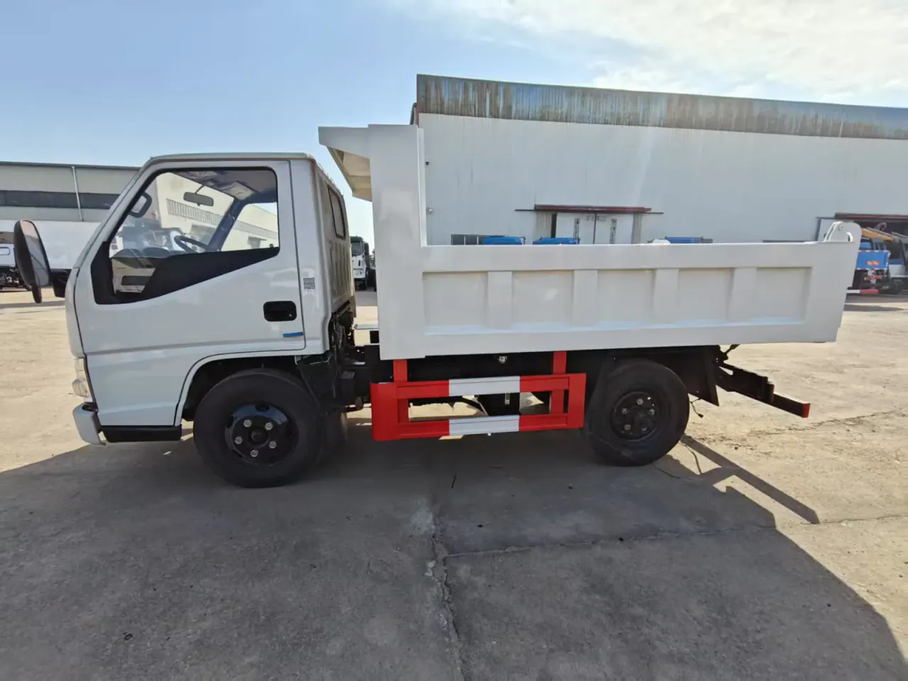 Side profile of a compact white dump truck with a short high-sided body