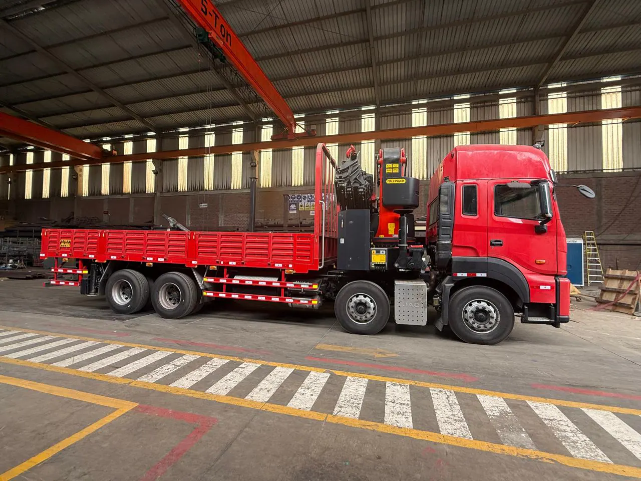 Full side profile of the red JAC 8x4 knuckle-boom crane truck in the workshop