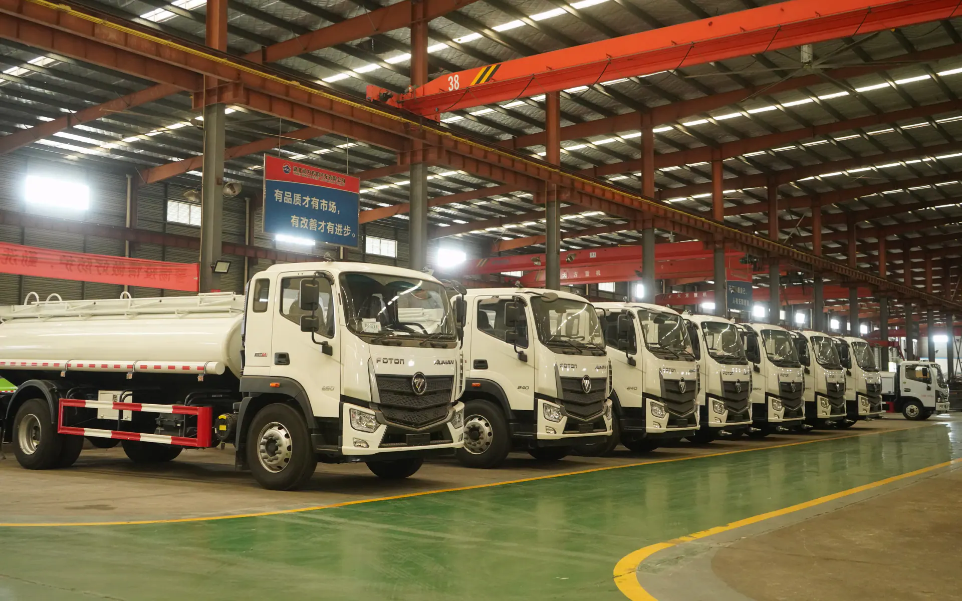 A lineup of completed white tanker trucks inside a special vehicle workshop