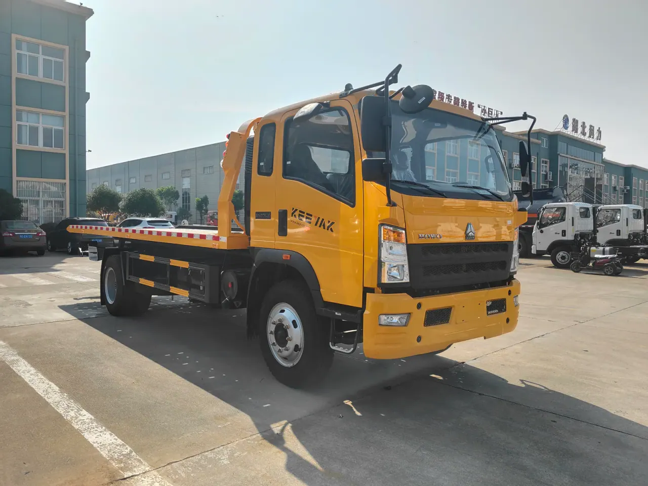 Yellow HOWO truck with a flat vehicle-recovery bed