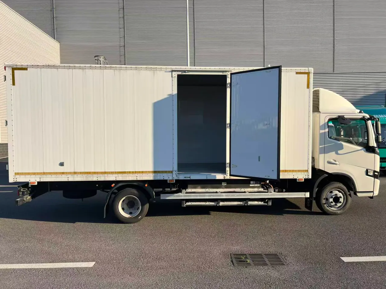 Full side view of a white box truck with its cargo-side door open