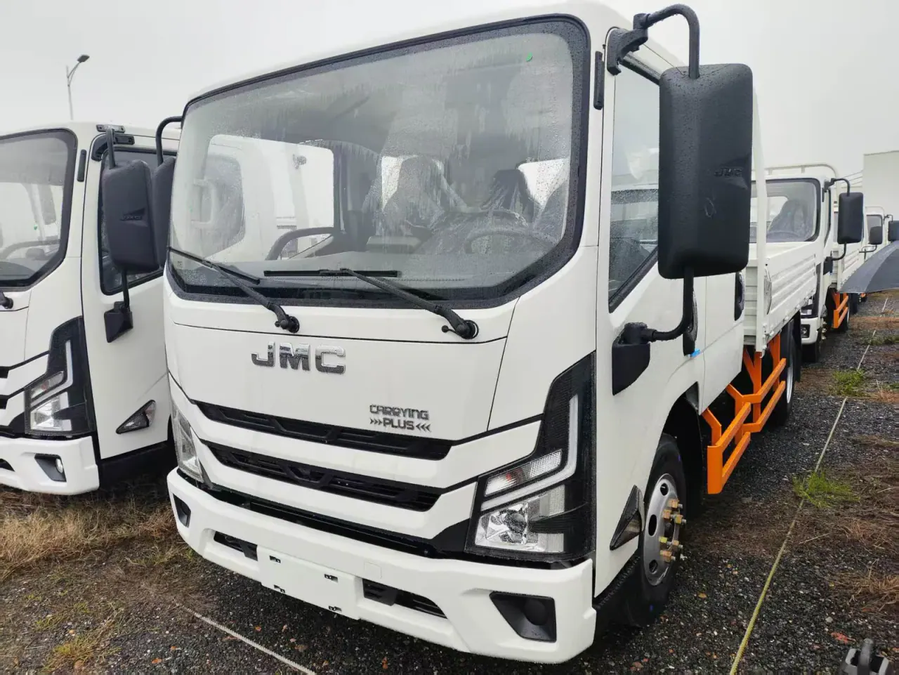 Camion blanc à double cabine à ridelles JMC vu de l'avant gauche