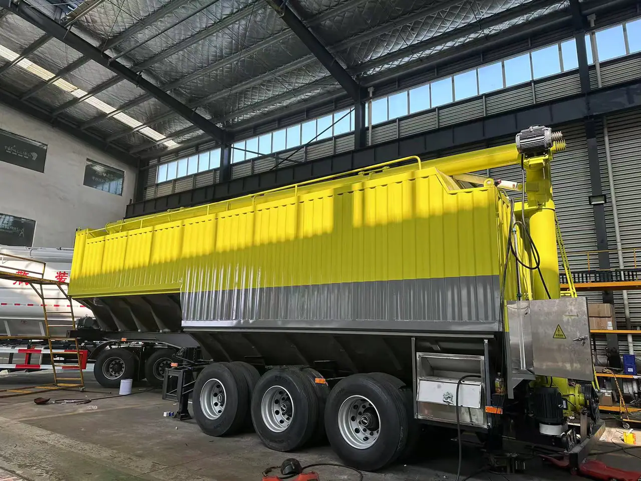 Yellow-and-grey three-axle bulk feed semi-trailer in the workshop