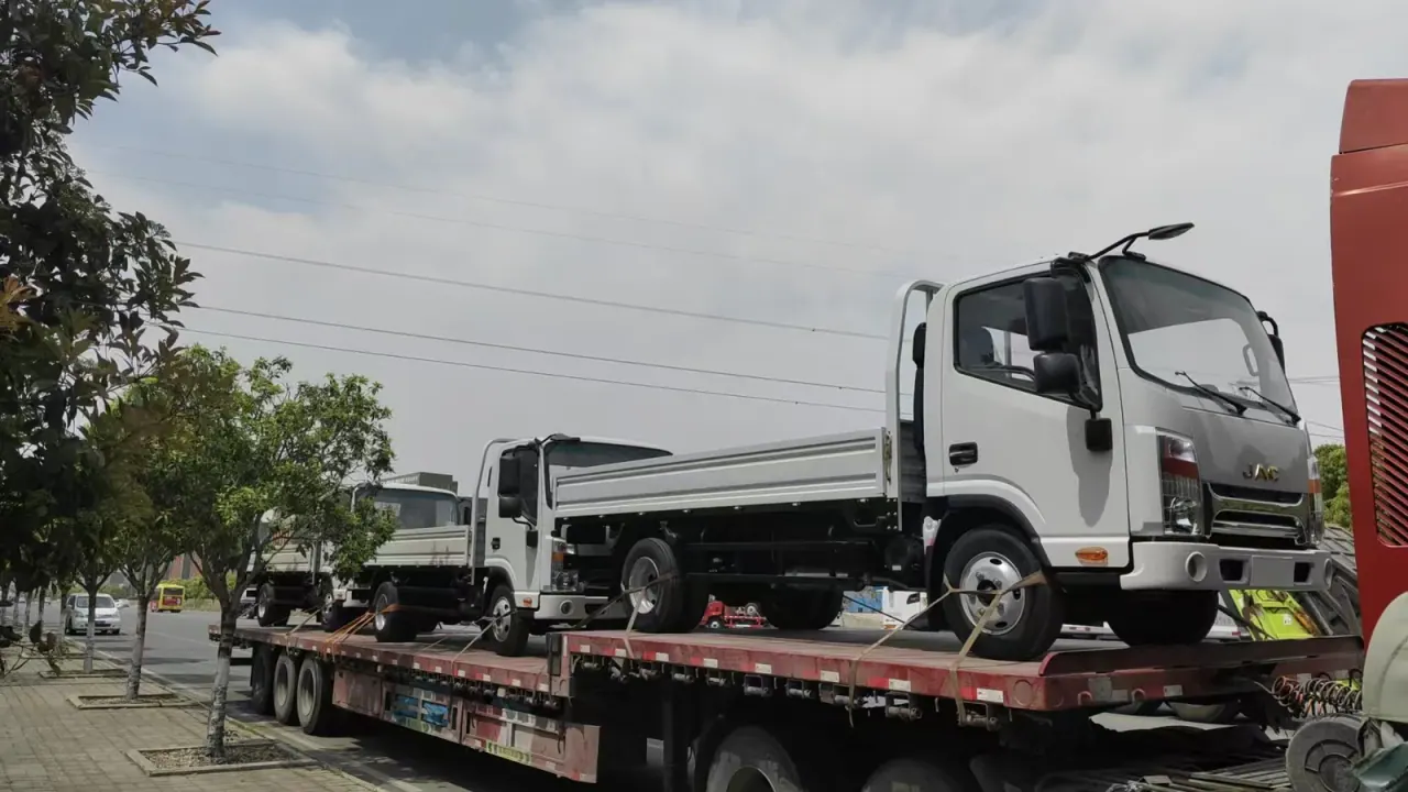 Side view of a JAC drop-side truck on a road transport platform