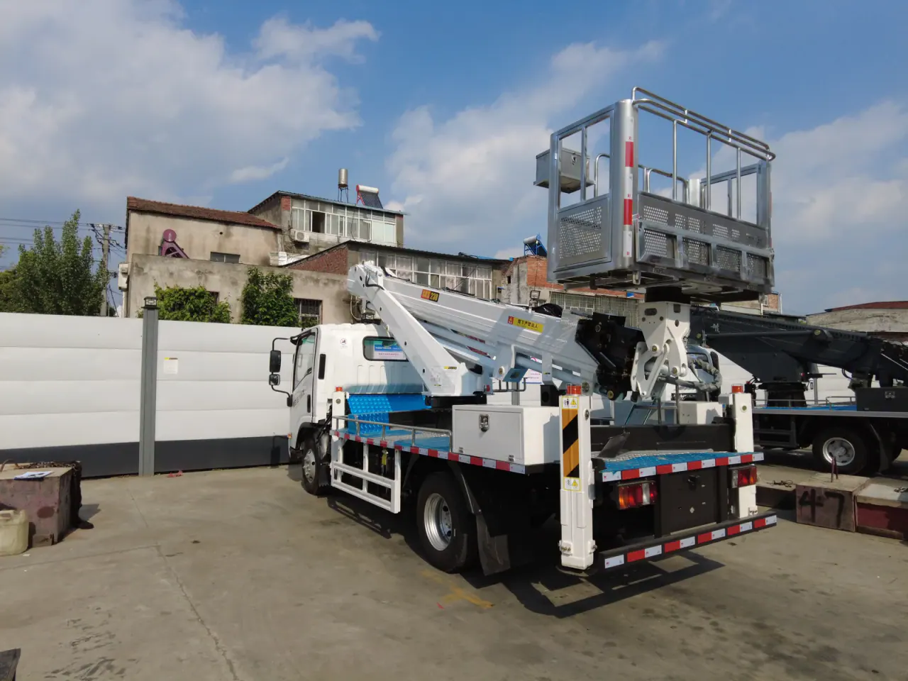 Rear three-quarter view of an aerial platform truck with basket and stabilizers