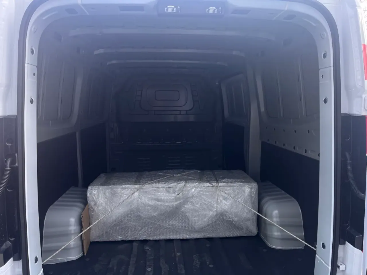Cargo compartment viewed through the open rear doors with a wrapped item inside