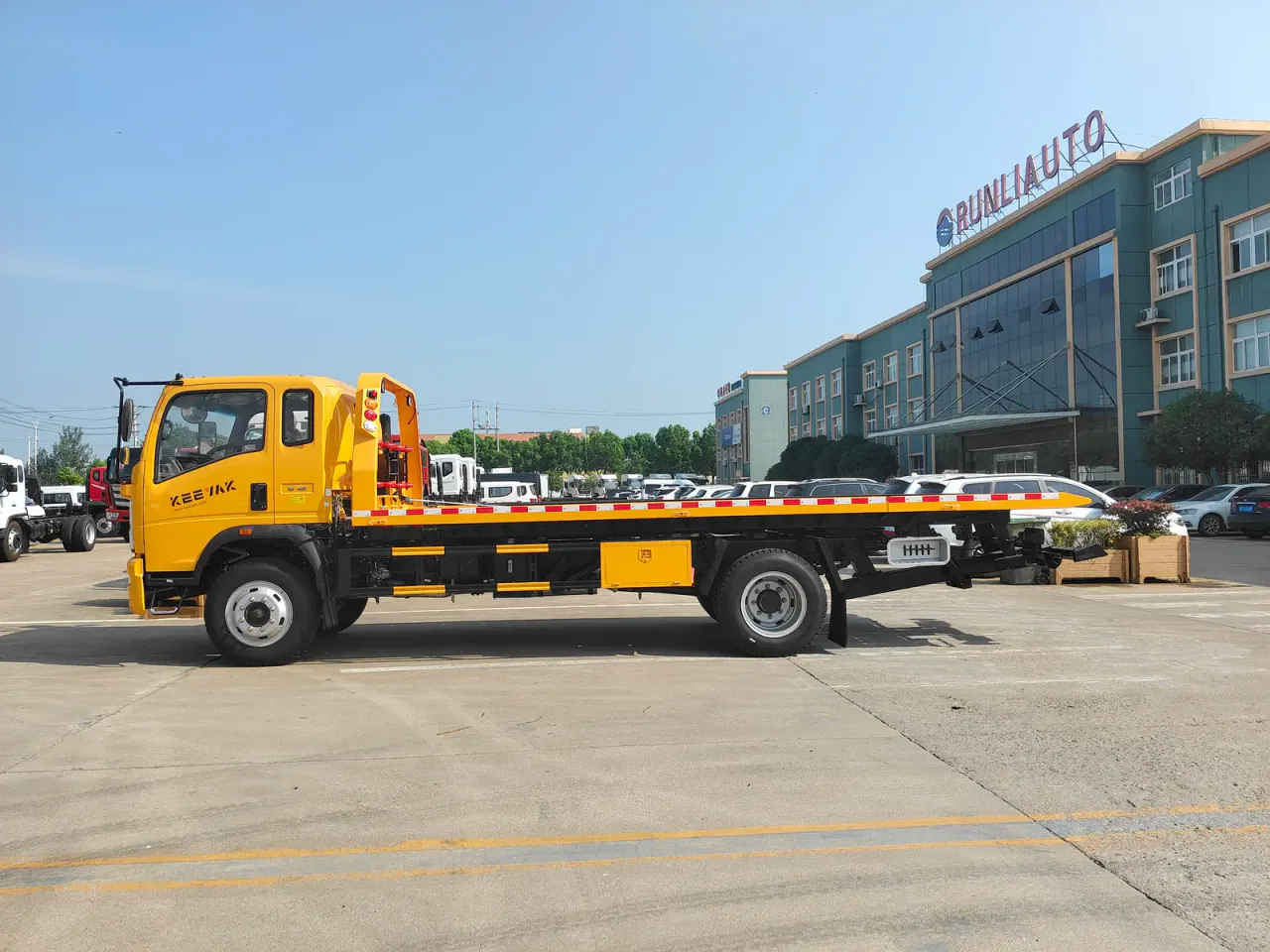 Yellow flatbed recovery truck shown in full side profile