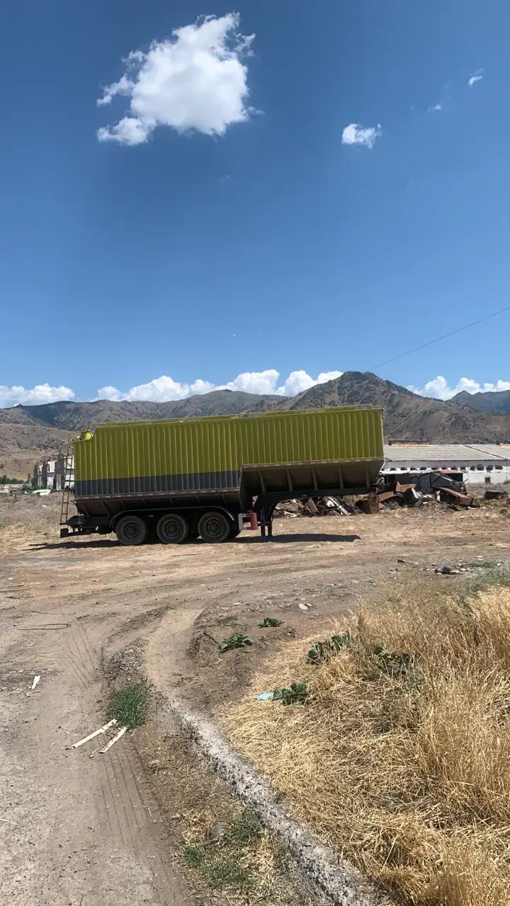Yellow bulk feed semi-trailer in an outdoor yard