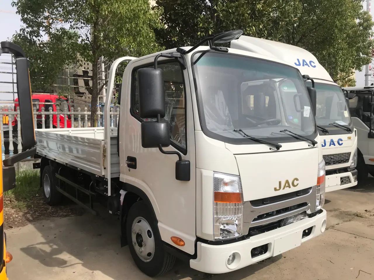 White JAC drop-side truck viewed from the opposite front angle