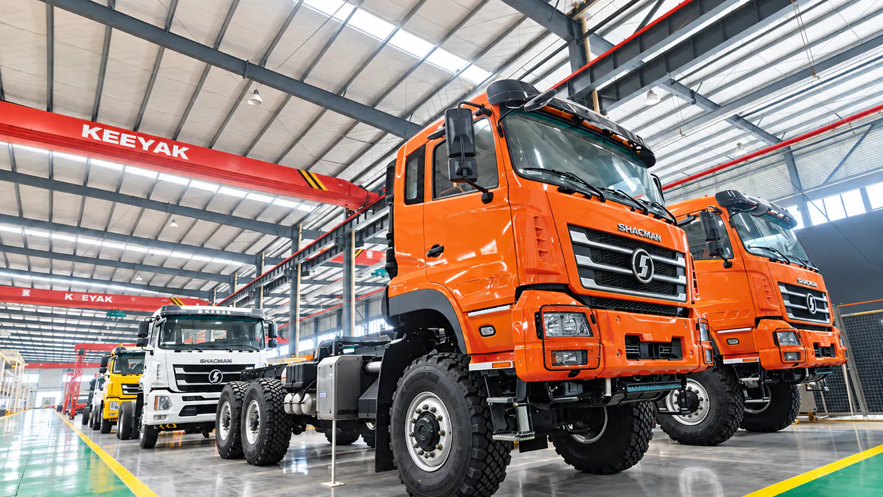 Truck chassis with orange, white and yellow cabs positioned inside the workshop.